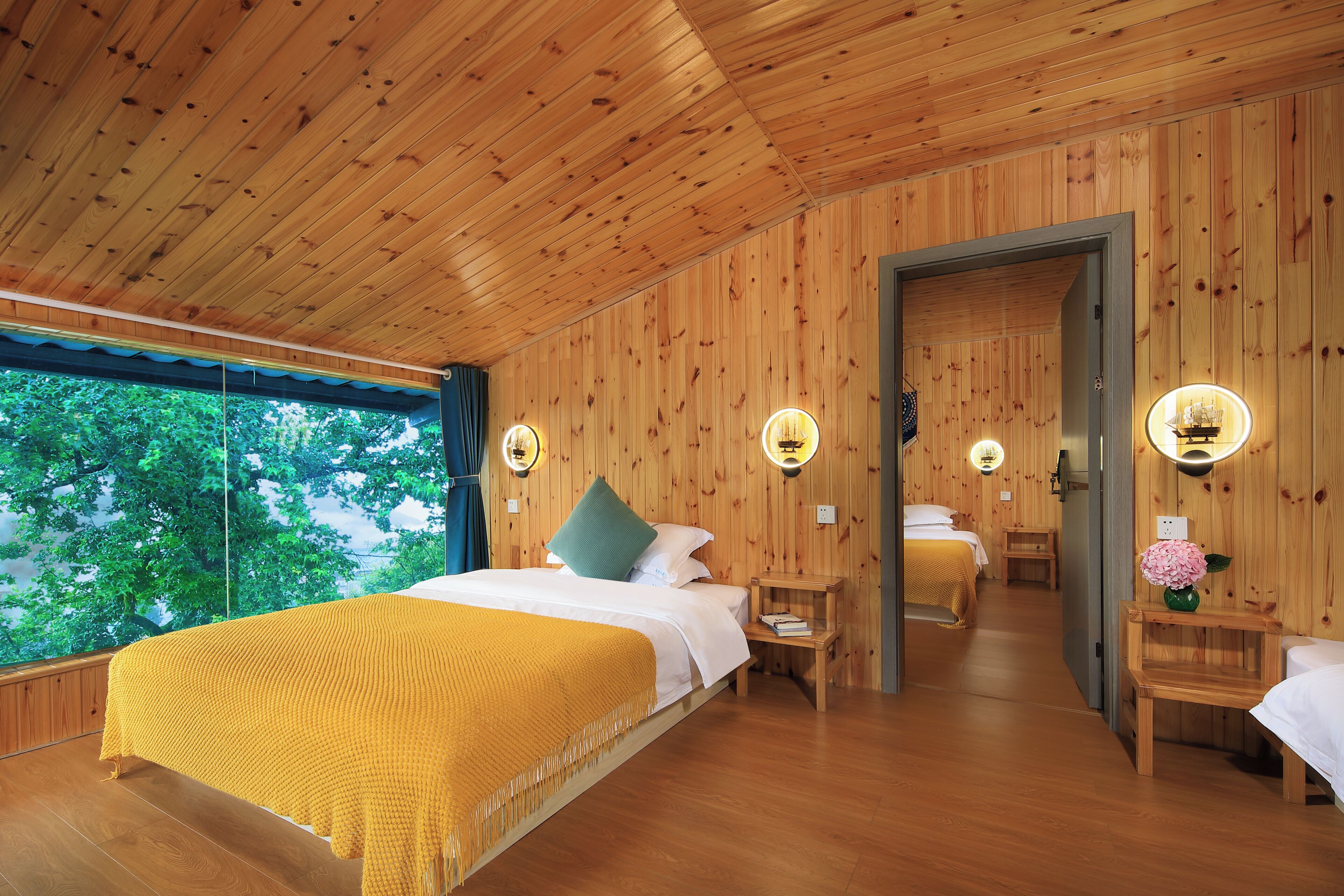 A wooden-paneled room with a bed, bedside tables, and a mirror.