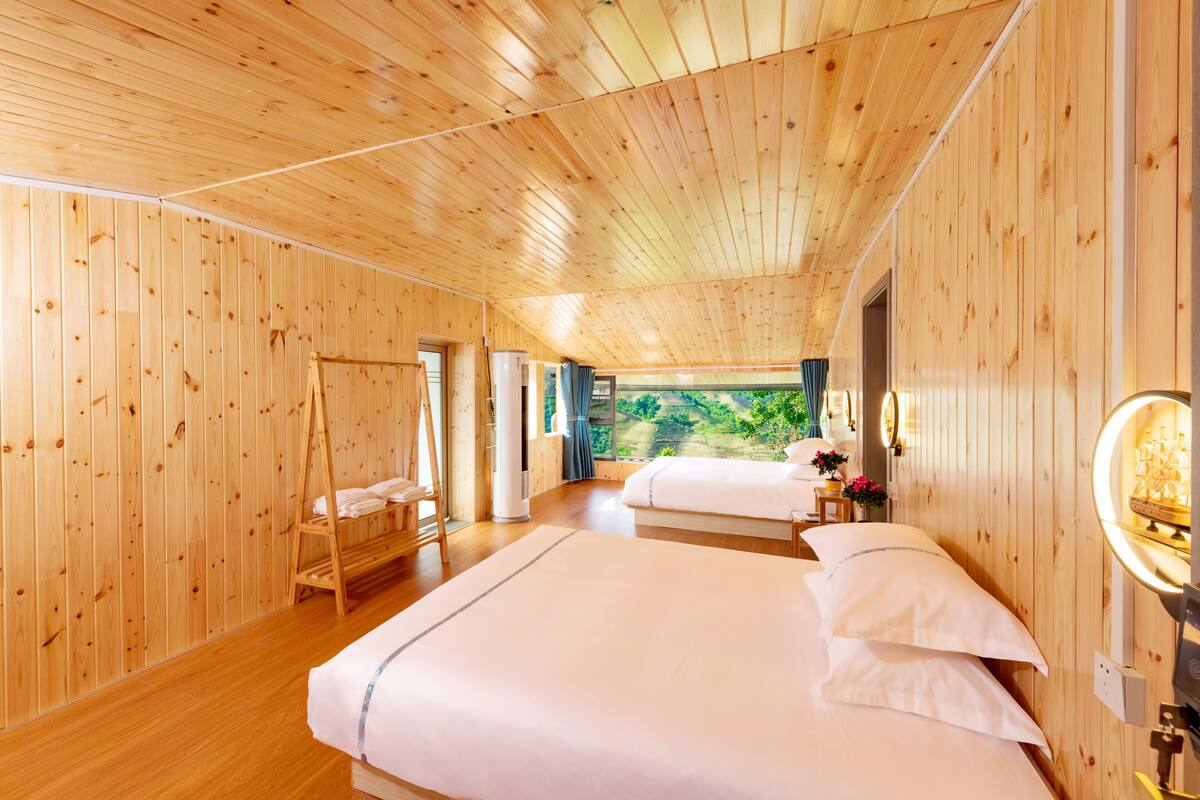 Una habitación con paneles de madera, dos camas, una escalera de madera y un ventanal grande.