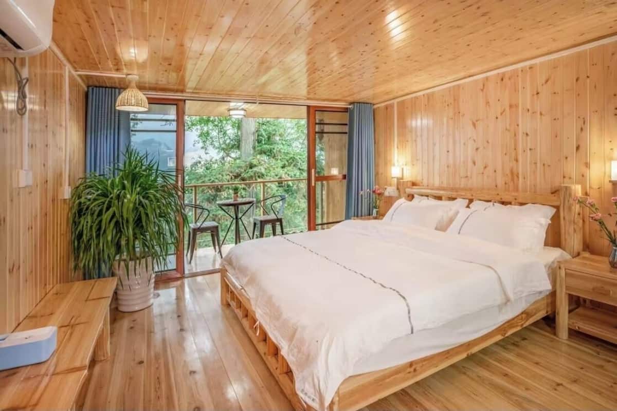 Un dormitorio con paneles de madera, una cama, un banco, una mesa y una planta en maceta.