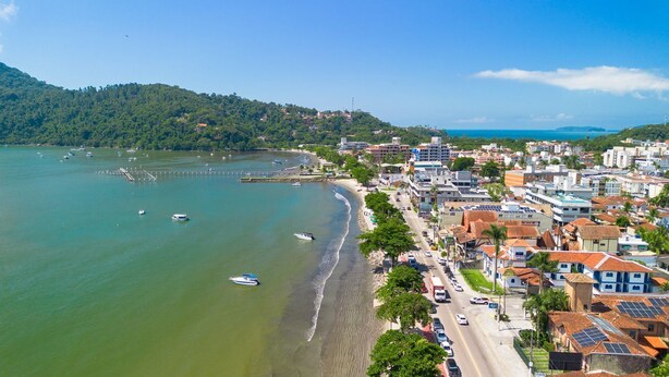 A coastal town with a beach, boats, and buildings along the shore. - Apto a 280m da Praia do Itagu c Piscina e Garagem (Ubatuba)
