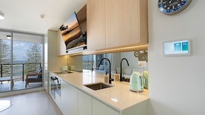 A modern kitchen with a large island, a built-in oven, and a view of the outdoors. - Waterfront, Pool, Balcony, Prime Location (The Entrance)