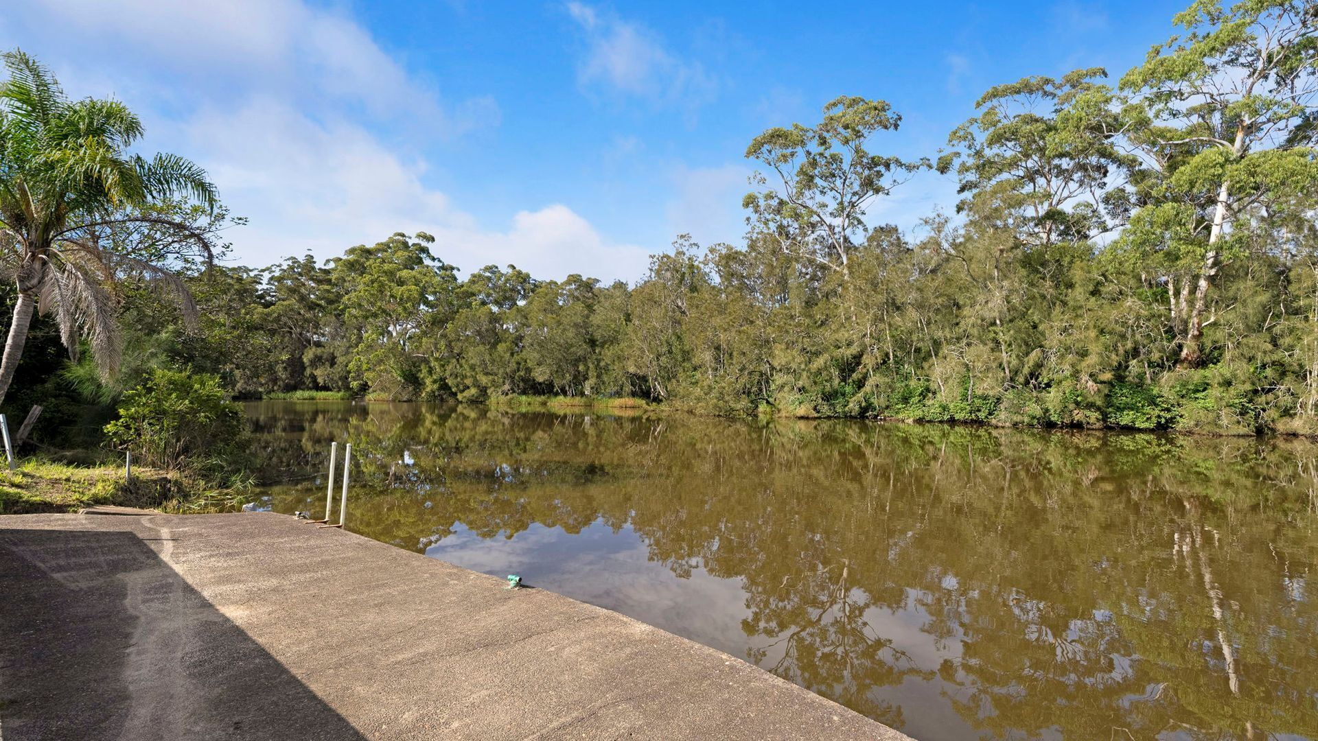A calm lake with a concrete walkway along the edge.