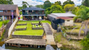 A modern house with a flat roof, a large deck, and a water feature in front.