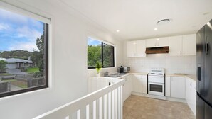 A modern kitchen with white cabinets, a stainless steel refrigerator, and a window overlooking a residential area.