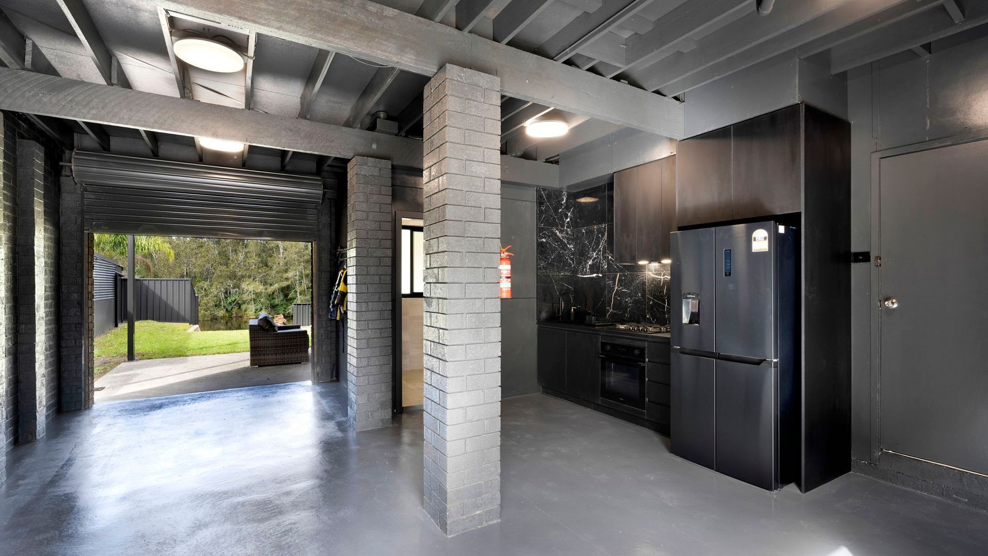 Een moderne keuken met een grote koelkast, een marmeren spatwand en een betonnen vloer.