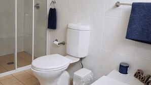 Kylpyhuone, jossa on wc, suihkukaappi ja pyyhekoukku.