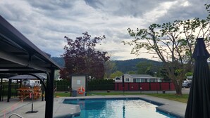 A swimming pool with a covered area, a lifebuoy, and a picnic table.