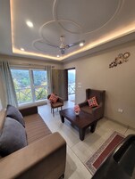 A modern living room with a sofa, armchairs, a coffee table, and a ceiling fan.