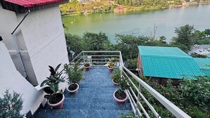 Una escalera conduce a una terraza con plantas en macetas, con vistas a un lago y montañas.