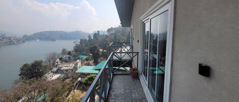 A balcony with a view of a body of water and distant hills.