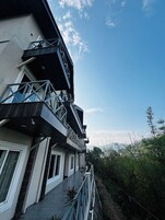Un edificio de varios pisos con balcones, una galería techada y vistas al entorno verde.