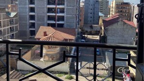 Un immeuble à plusieurs étages doté de balcons, un ciel dégagé et des bâtiments urbains environnants.