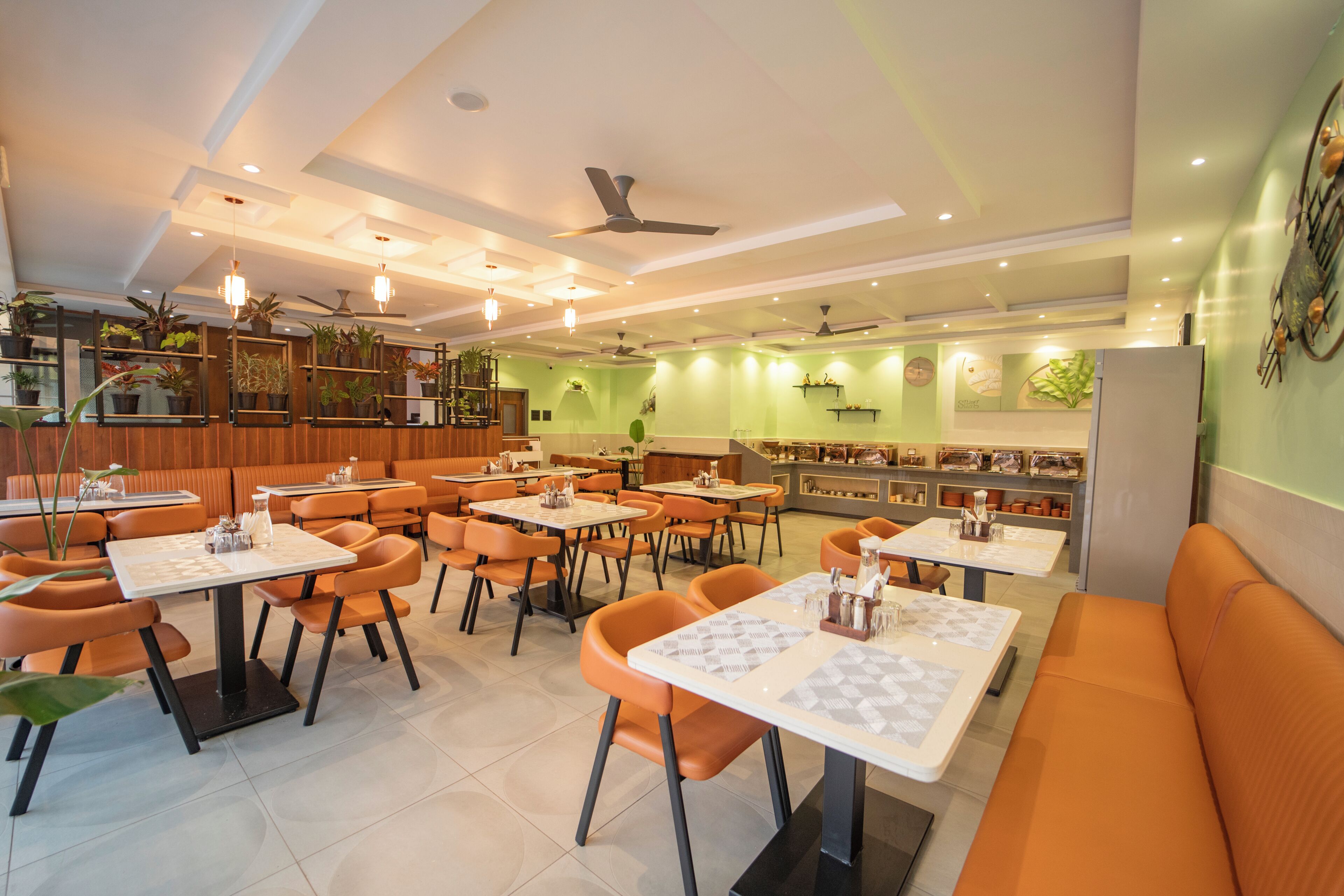 Un restaurante con varias mesas y sillas, ventiladores de techo y plantas decorativas.
