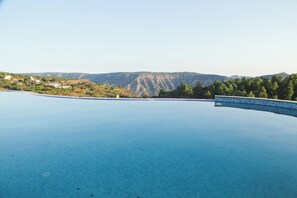 A clear swimming pool with a view of distant hills and a few buildings.