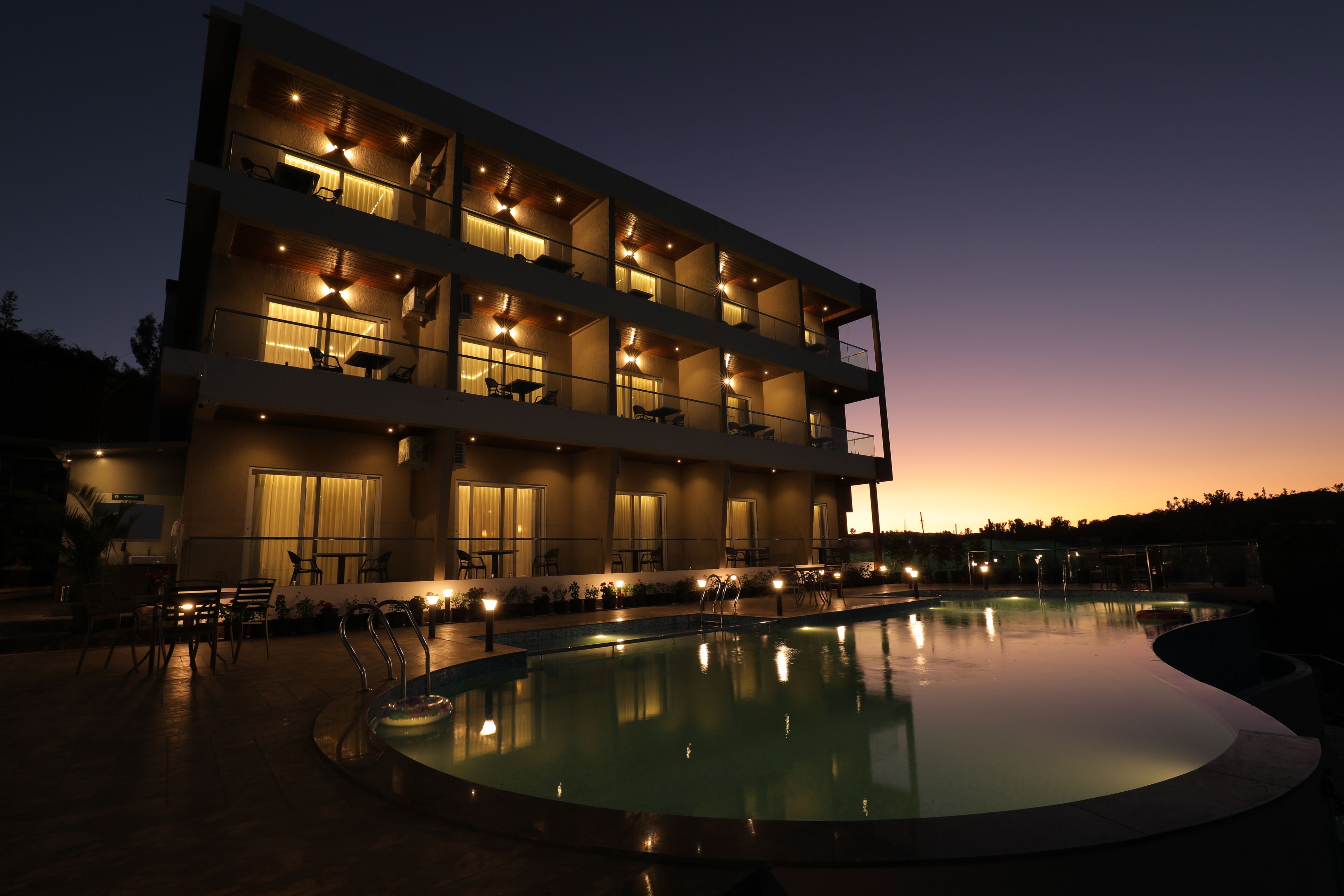 A multi-story hotel with balconies, a swimming pool, and outdoor seating.