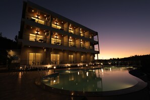 A multi-story hotel with balconies, a swimming pool, and outdoor seating.