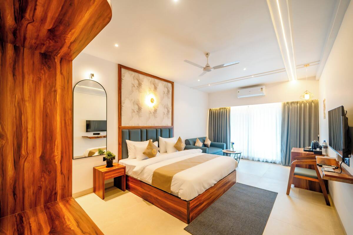 Camera d'albergo moderna con un letto grande, una scrivania, una sedia, una televisione e una ventola a soffitto.