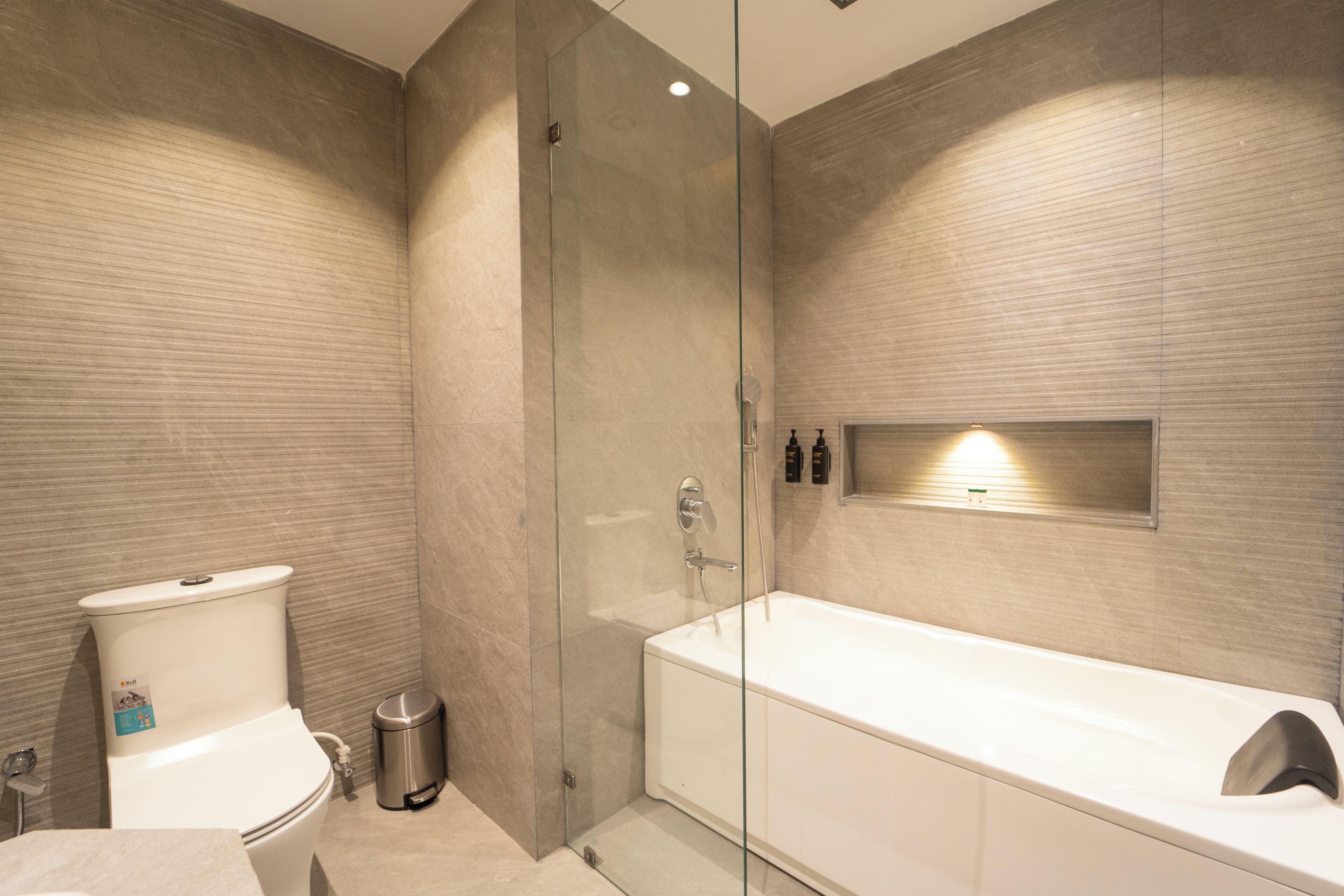 Un baño moderno con ducha de mampara de vidrio, inodoro blanco y una bañera grande.
