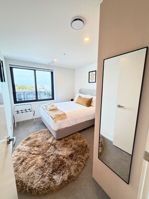Ein modernes Schlafzimmer mit einem großen Fenster, einem Bett mit einem flauschigen Teppich und einer Tür mit einem Spiegel.