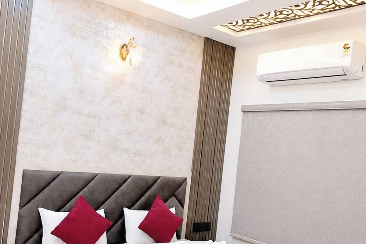 Una habitación de hotel moderna con una cama grande, un ventilador de techo, un equipo de aire acondicionado y un panel decorativo en la pared.