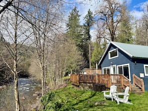 Een chalet met terras, een rivier en een bebost gebied.