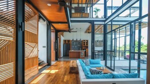 Ein modernes Interieur mit Holzboden, einem weißen Sofa und einer Glaswand mit Blick auf einen Pool.