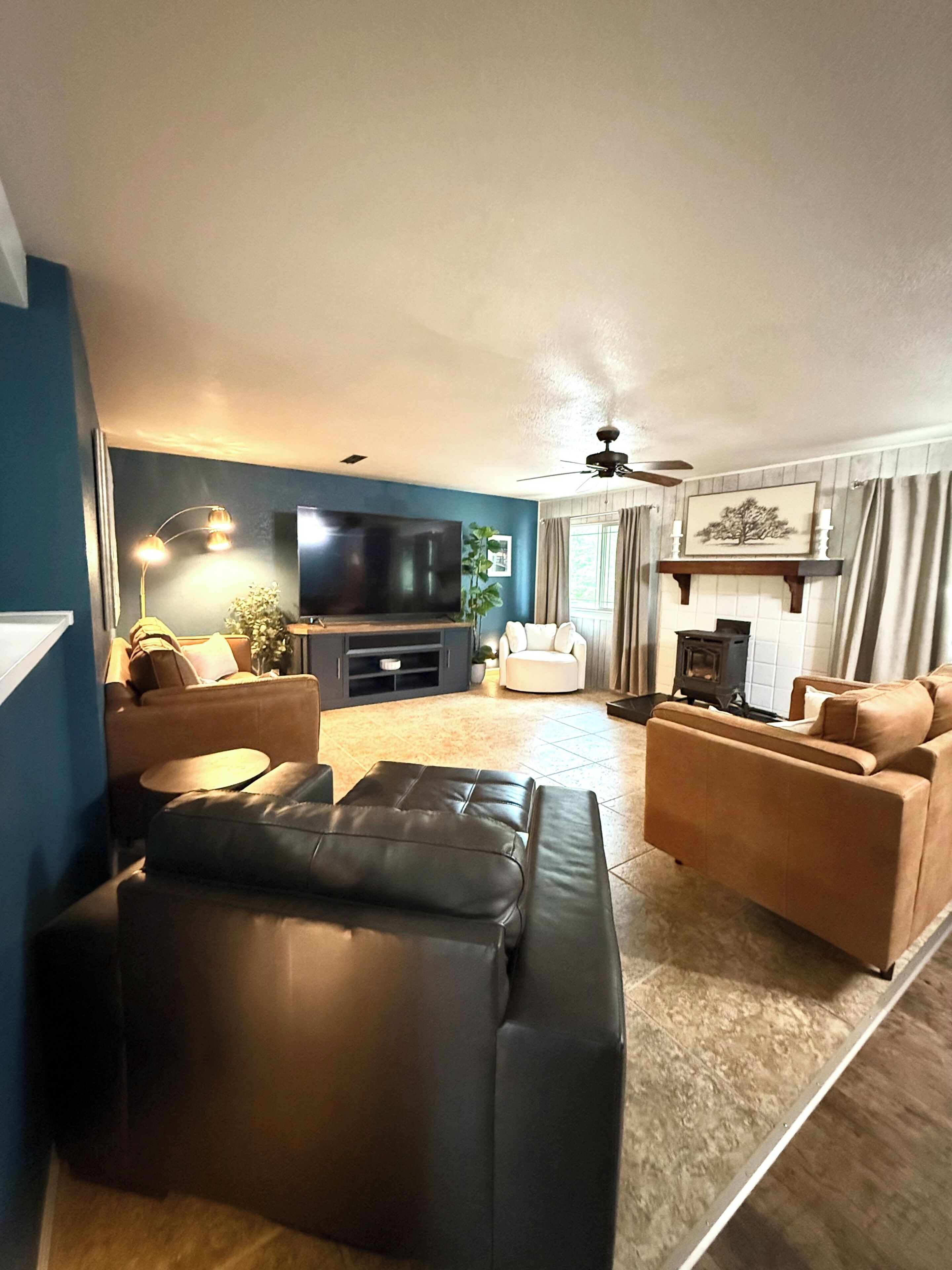 Una sala de estar con televisor, sofás, chimenea y ventilador de techo.