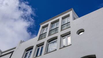 Un edificio de varios pisos con fachada blanca, numerosas ventanas y balcones.