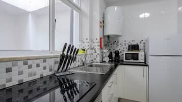 Una cocina moderna con encimera negra, pileta de acero inoxidable y muebles de cocina blancos.