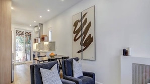 A modern living room with a sofa set, a dining area, and a kitchen in the background.