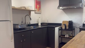 A modern kitchen with a refrigerator, sink, and coffee maker.