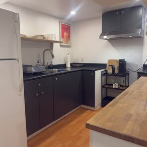A modern kitchen with a refrigerator, sink, and coffee maker.