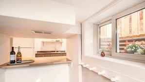 A modern kitchen with a window, a bottle of wine, and a small decorative item on the windowsill.