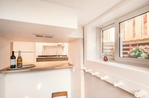 A modern kitchen with a window, a bottle of wine, and a small decorative item on the windowsill.