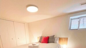 A bedroom with a bed, a nightstand, a window, and a wardrobe.
