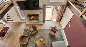 Ein geräumiges Wohnzimmer mit Kamin, einer Couch, einem Sessel und einem Couchtisch.