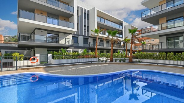 Ein modernes Mehrfamilienhaus mit Swimmingpool, Balkonen und einem eingezäunten Garten.