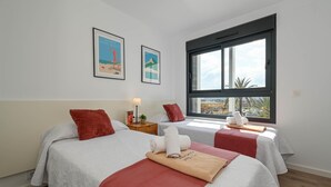Ein Hotelzimmer mit zwei Betten, einem großen Fenster und Kunstwerken an der Wand.