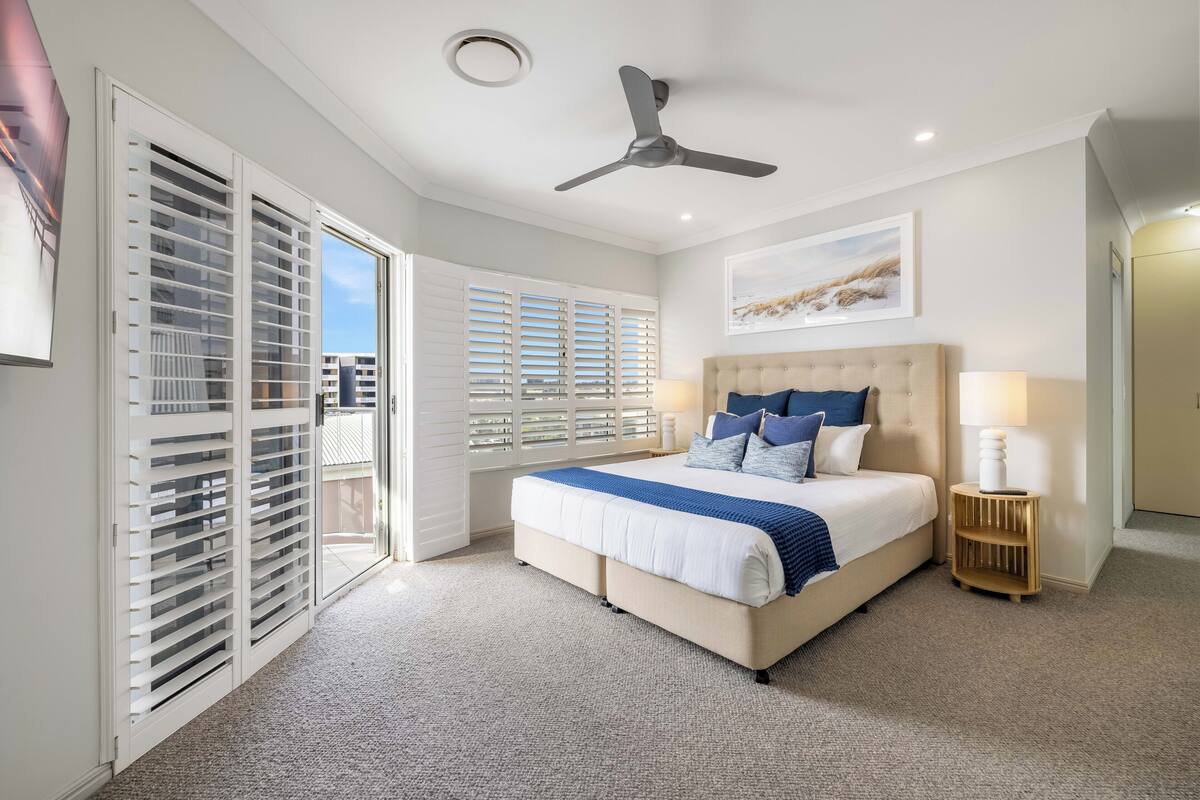 Une chambre à coucher avec un lit, un ventilateur de plafond et une vue par la fenêtre.