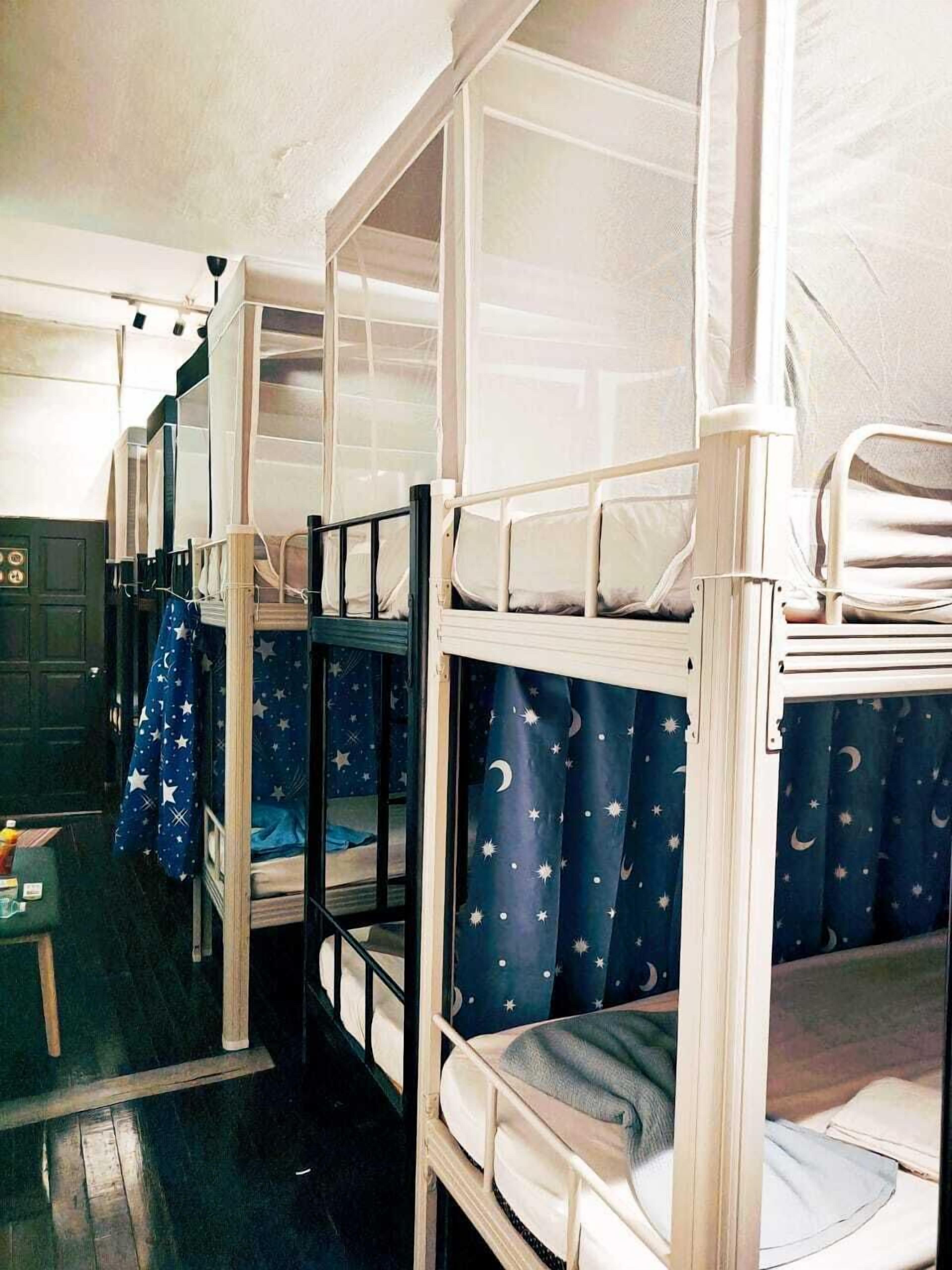 Dormitorio con literas, ventana, una mesita con objetos y una puerta.