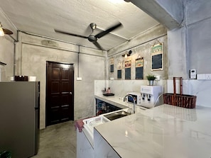 A kitchen with a refrigerator, microwave, sink, and ceiling fan.