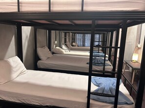 A bunk bed room with two beds, a bedside table, and a window. - Pirate's Cove Hostel (Malacca City)