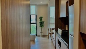 A modern kitchen with wooden cabinets, a refrigerator, and a dining area with a table and chairs. - Torre Margot (Guadalajara)