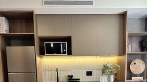 A modern kitchen with a microwave, wooden cabinets, and a dining table set for four. - Torre Margot (Guadalajara)