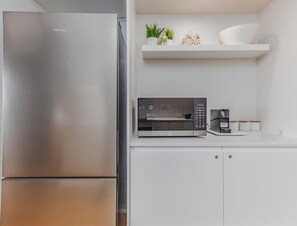A kitchen with a stainless steel refrigerator, a microwave, and a coffee maker on a white countertop. - The Sand Resort | Coastal One Bedroom with park view (Tweed)