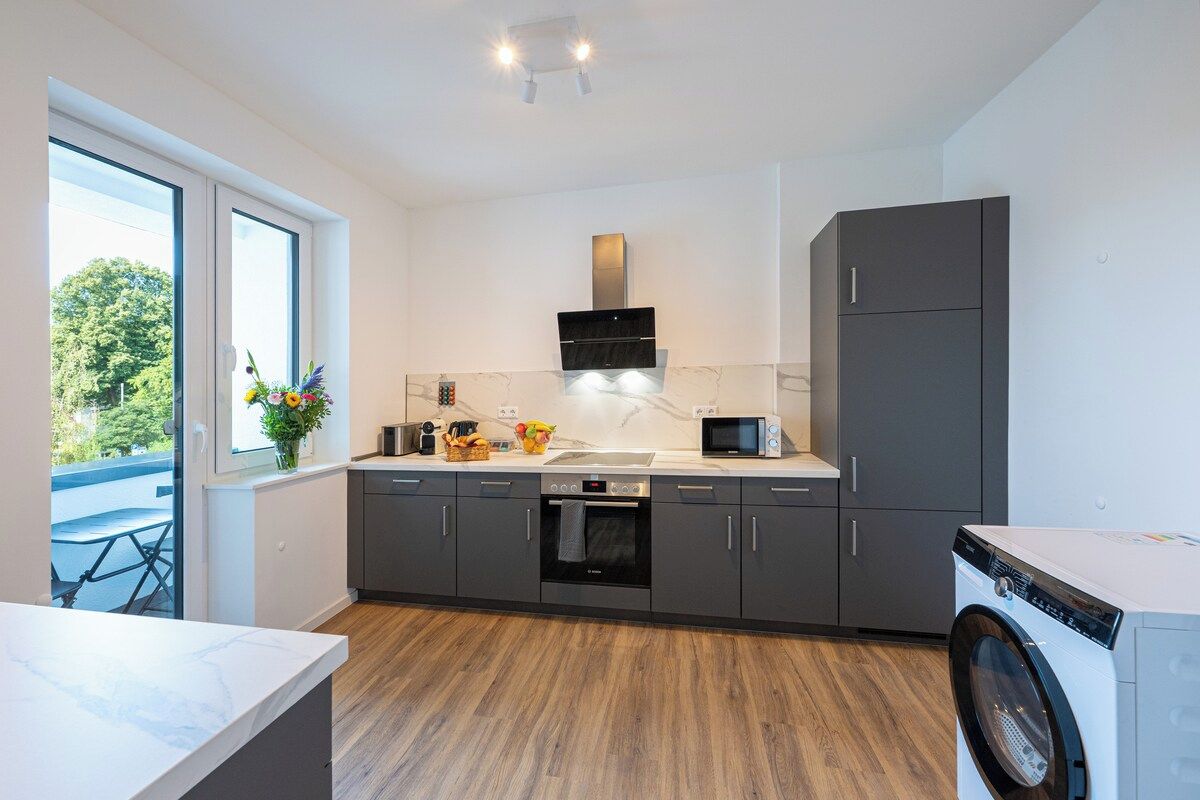A modern kitchen with a built-in oven, microwave, and a washing machine.