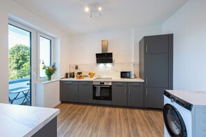 A modern kitchen with a built-in oven, microwave, and a washing machine. - Captain’s Nest: Stylish, near harbour, 2 parking spaces (Bremerhaven)