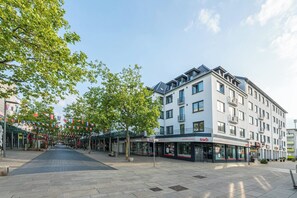 A modern building with multiple floors, a covered outdoor seating area, and a clear sky. - Captain’s Nest: Stylish, near harbour, 2 parking spaces (Bremerhaven)