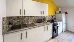 Cozinha com armários brancos, micro-ondas, torradeira e lava-louças.