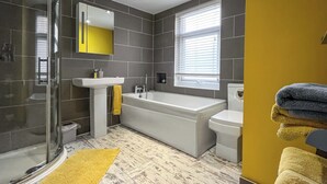 Ein modernes Badezimmer mit Duschkabine aus Glas, einem weißen Waschbecken, einer Badewanne und einem WC.